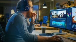 Man sat in front of desktop computer using the best headphones for video editing
