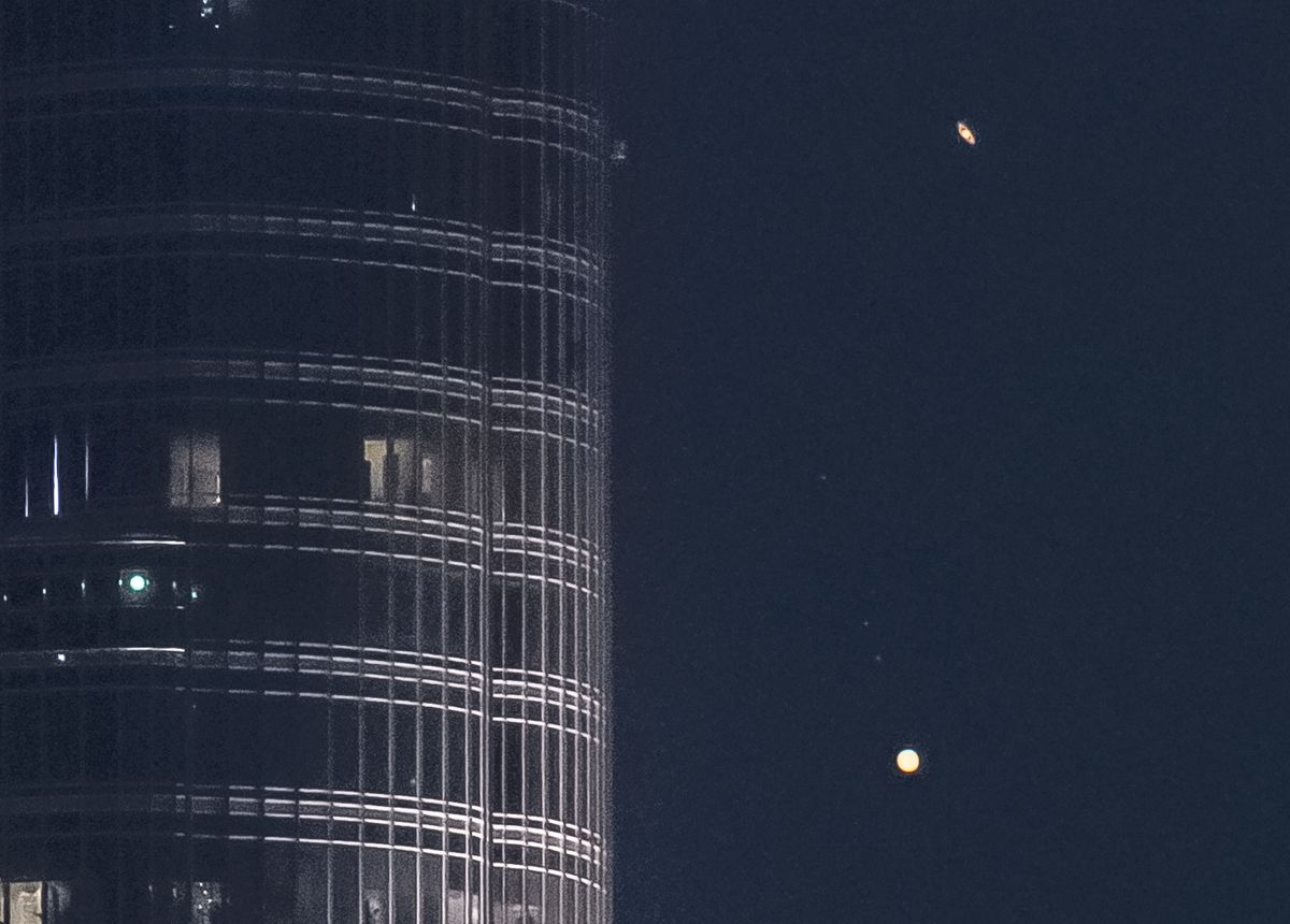 The rings of Saturn glide above Jupiter as the two planets pass near Burj Khalifa, the world&#039;s tallest building.