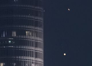 The rings of Saturn glide above Jupiter as the two planets pass near Burj Khalifa, the world's tallest building.