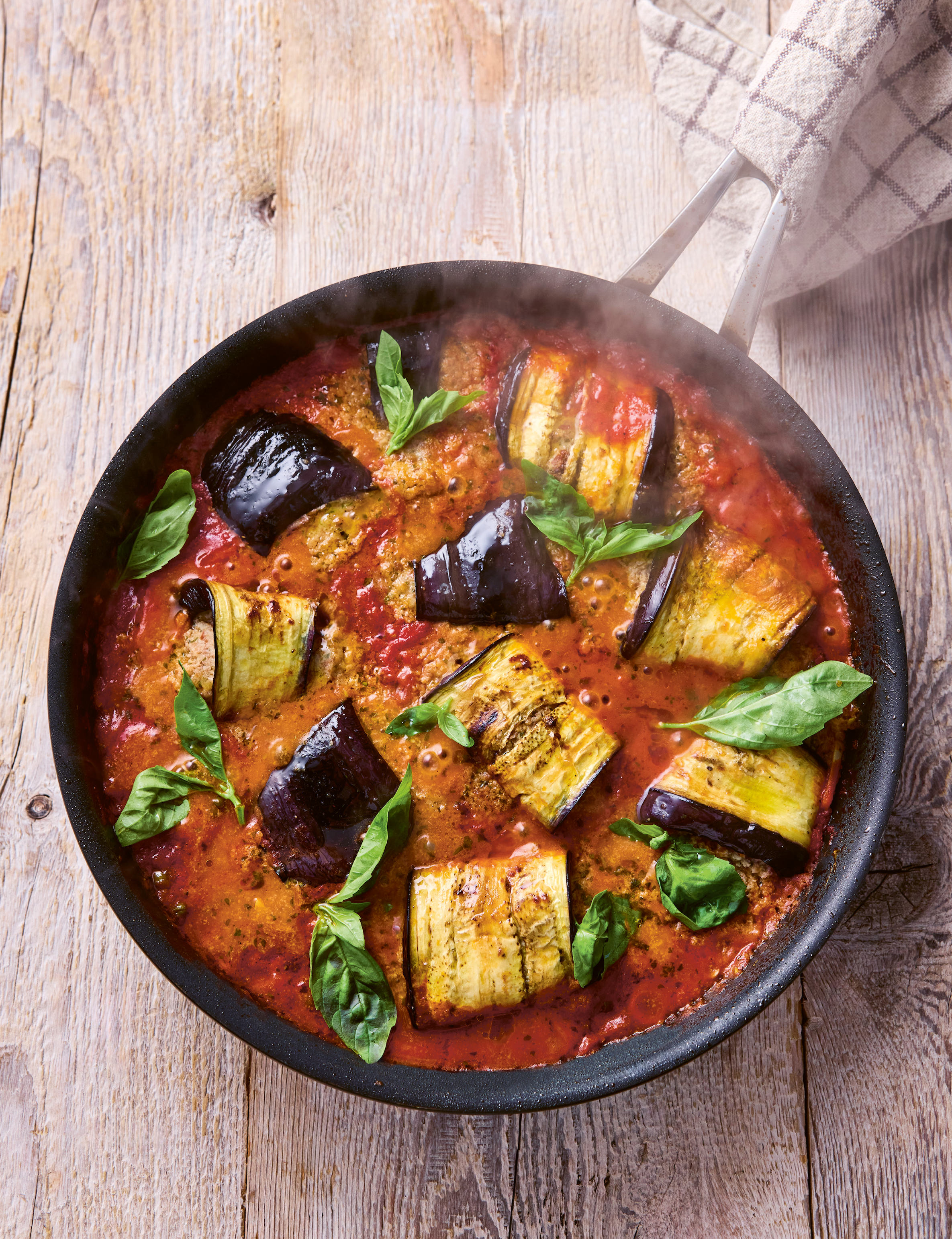A frying pan full of aubergines in tomato sauce