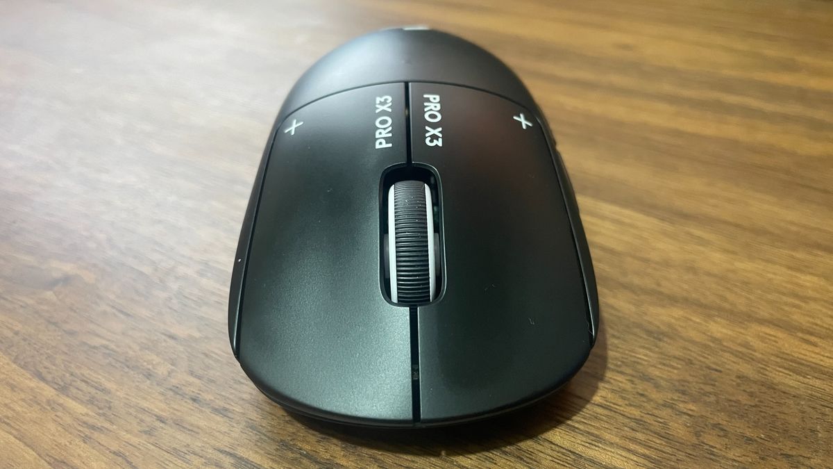 A Logitech G Pro X3 Superstrike gaming mouse on a wooden desk.