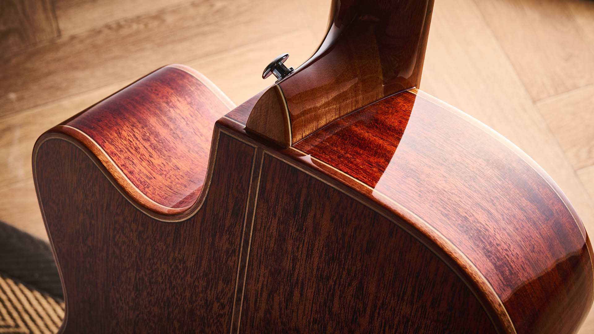 Harley Benton CLC-650SM-CE: the affordable cutaway electro-acoustic has a black top, natural back and sides, with an attractive arm-rest and tortoiseshell pickguard, and is here photographed against a wooden floor.