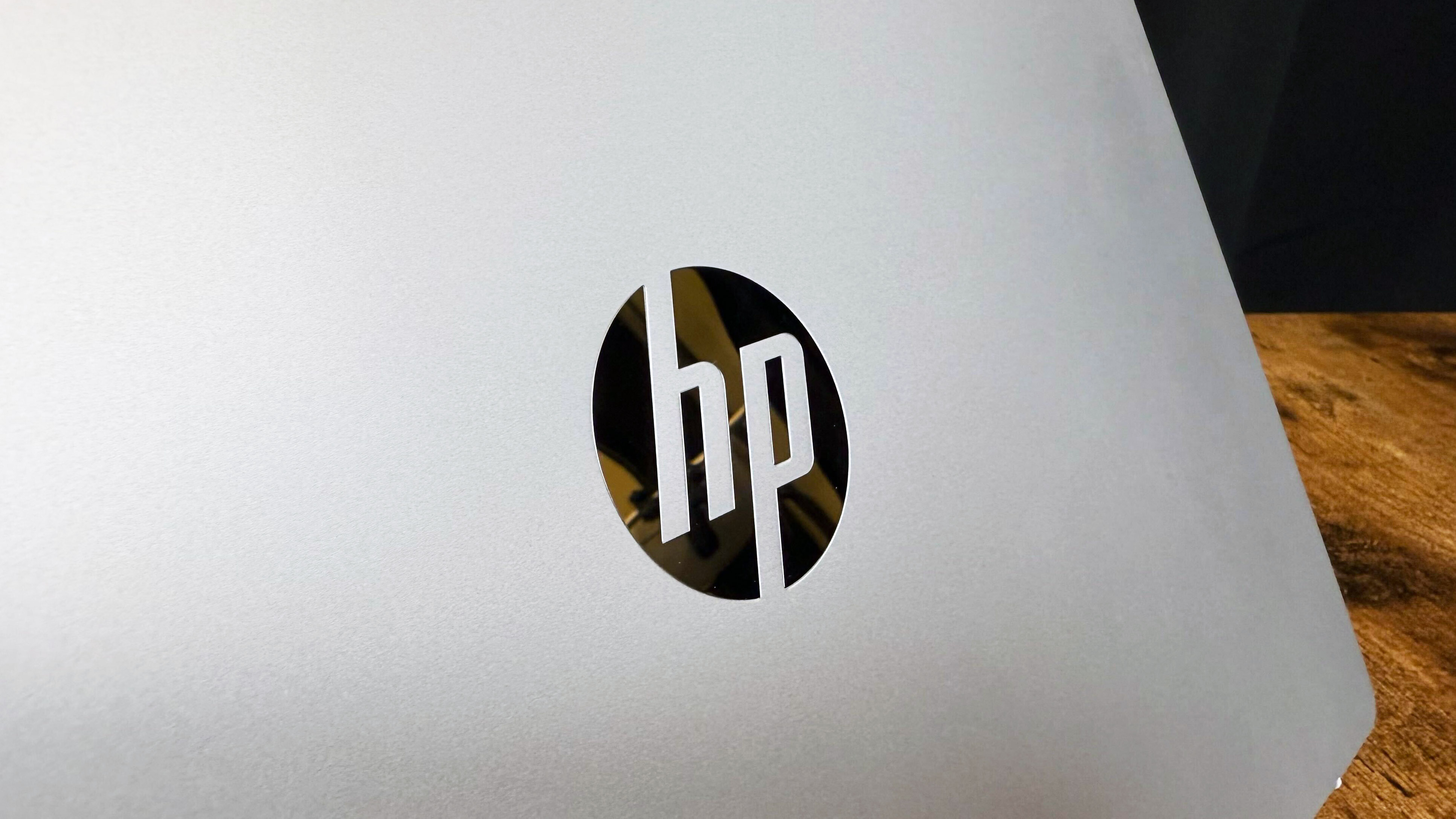 HP OmniBook 5 14 AI PC on a wooden table against a black backdrop.