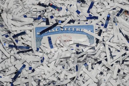 Social Security Card partially hidden amongst shredded documents. Document shredding, identity theft and fraud concept