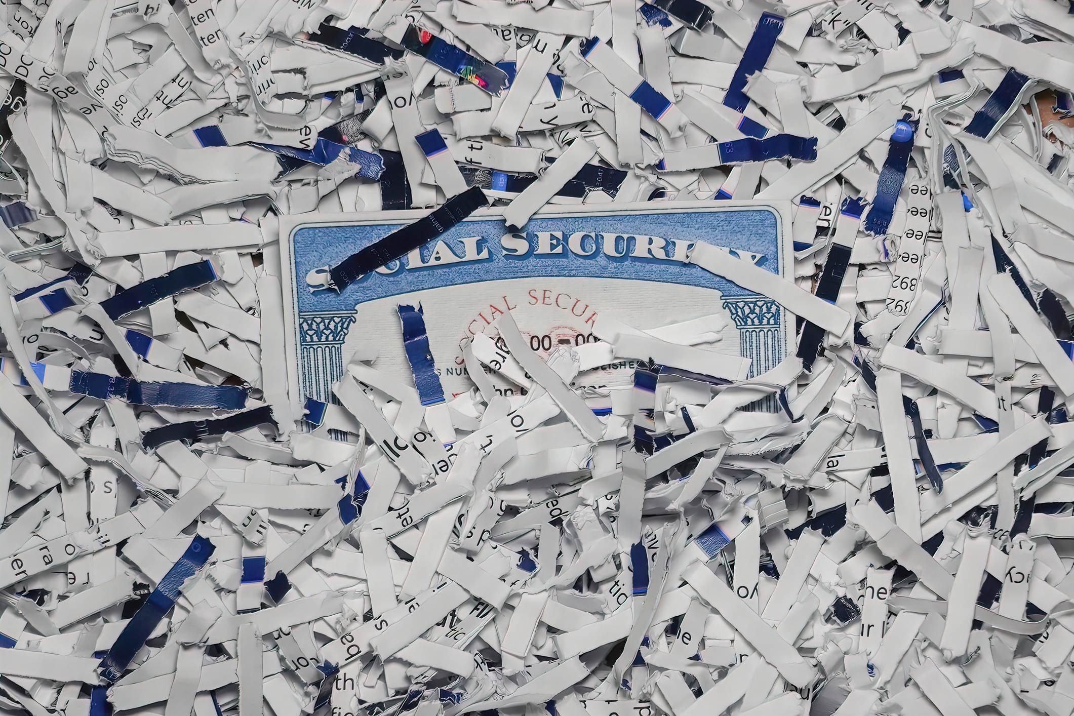 Social Security Card partially hidden amongst shredded documents. Document shredding, identity theft and fraud concept