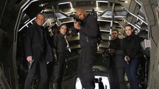 Characters from "Marvel's Agents of S.H.I.E.L.D" stand, armed in an aircraft