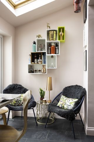 The living area of the kitchen extension has two armchairs, an Art Deco-style side table and cube shelving
