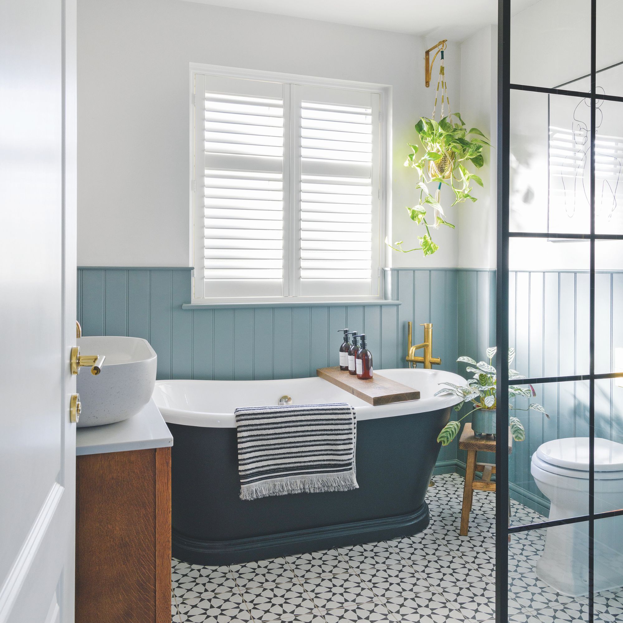 White painted bathroom with blue wall panelling and a blue freestanding bath