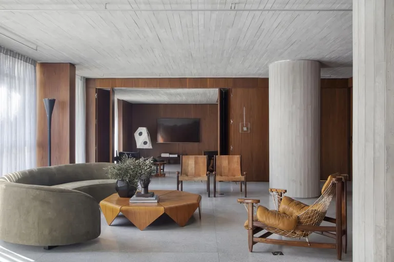 DN apartment by Bruno Carvalho Arquitectos features a green curved sofa, a brown low-rise table with brown chairs.