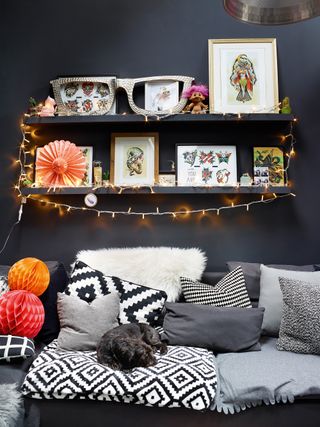 Floating shelves with dark grey walls and monochrome cushions on sofa