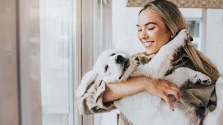 Easy ways to teach your dog new tricks — blonde lady cuddling white dog