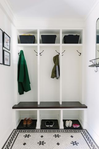 Built-in white entryway storage with hanging coats and baskets overhead.