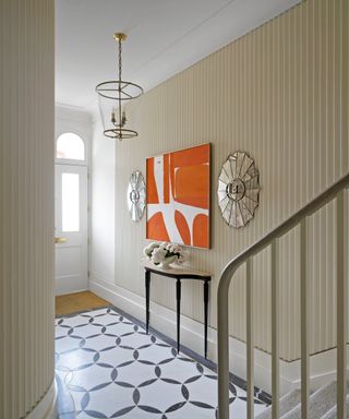 entrance hall with fluted edged wall panelling, statement orange artwork, console table and patterned floor