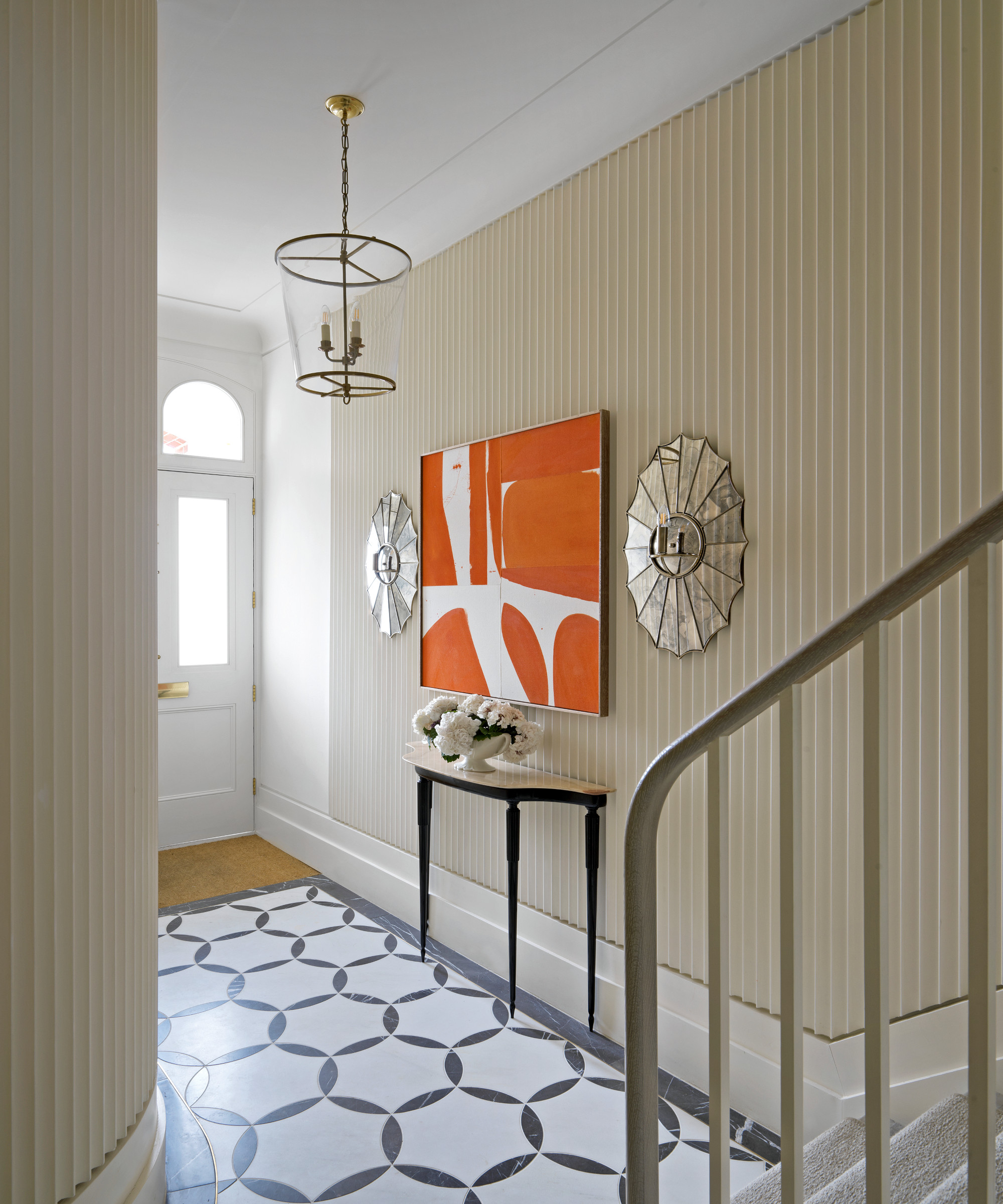 entrance hall with fluted edged wall panelling, statement orange artwork, console table and patterned floor