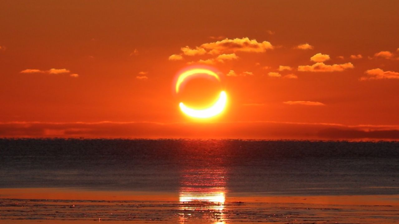 partial solar eclipse during sunrise, the sun looks like a pair of horns rising above the horizon.