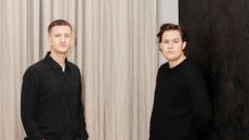 Youth Studio, two men wearing black standing in front of a curtain