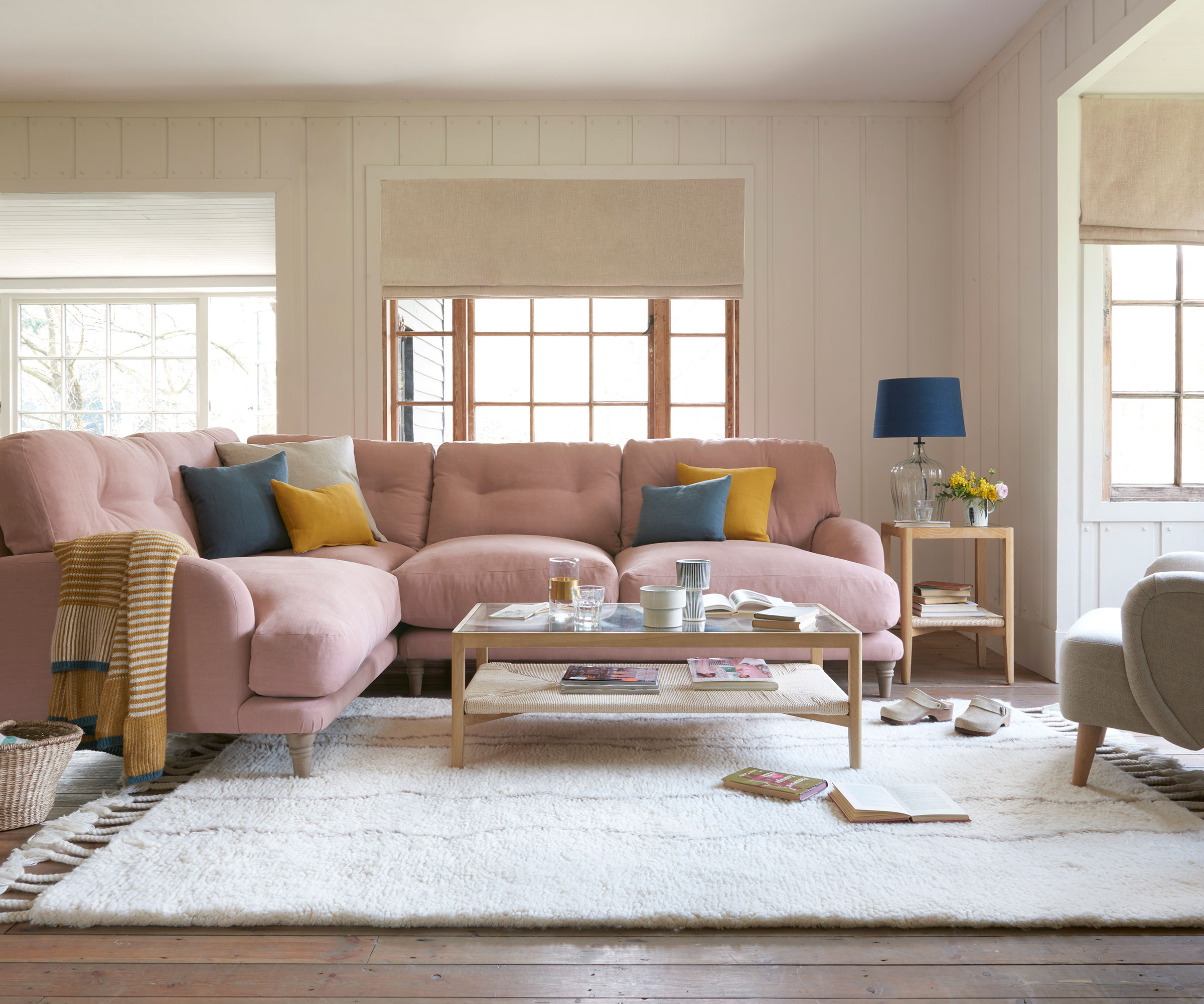 cost neutral living room with low ceilings and pink corner sofa in room with cream wall panelling