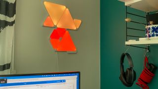 Nanoleaf Shapes hohkaa oranssina toimiston seinällä