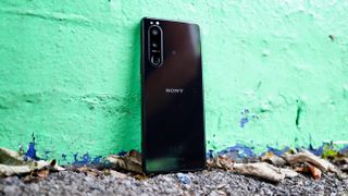 En svart Sony Xperia 5 III lutad mot en grön vägg.