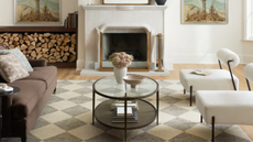 living room with a checker printed rug, white chairs, a brown couch, and a large shelf for firewood