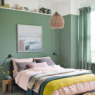 Green bedroom with bedside lamps and blankets on the bed