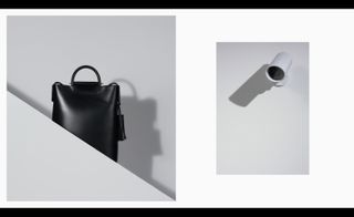 Left, a tall black leather bag behind a small grey diagonal wall. Right, a round white camera mounted on a wall.