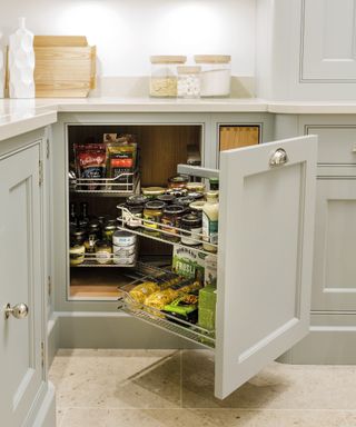 An example of kitchen cupboard storage ideas with a magic corner system in pale gray cabinetry.