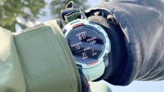 Garmin Instinct 3 on a user's wrist shown up-close in between a ski glove and jacket