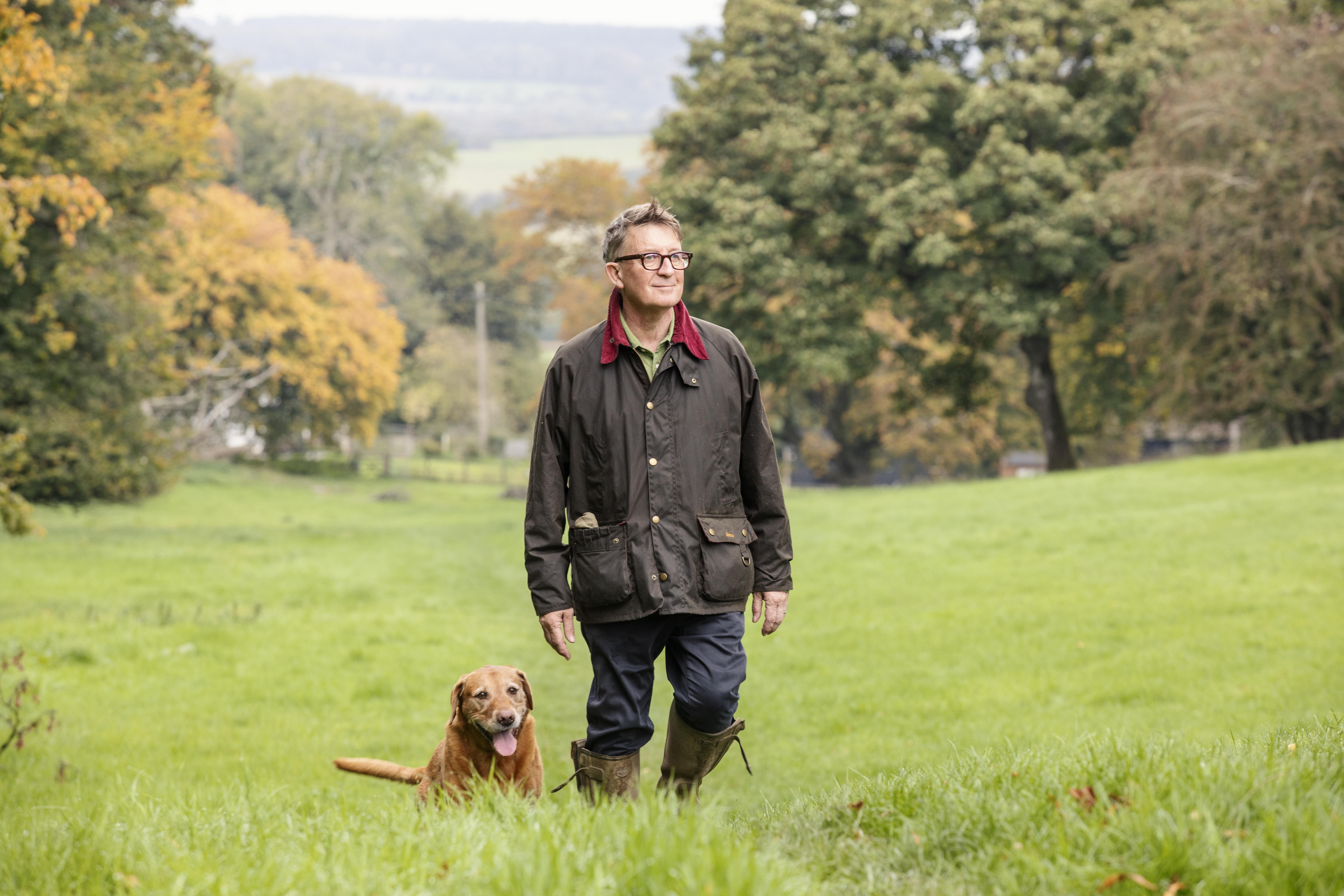 Mark Hedges and Tiger the red labrador walking through a grassy field