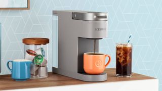 Keurig K-Slim on a wooden countertop with a hot and an iced coffee