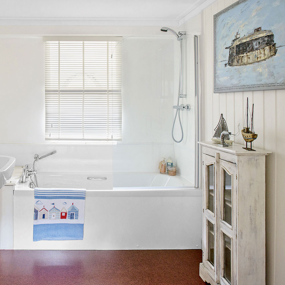 bathroom with white bathtub, wall panelling and deep red flooring