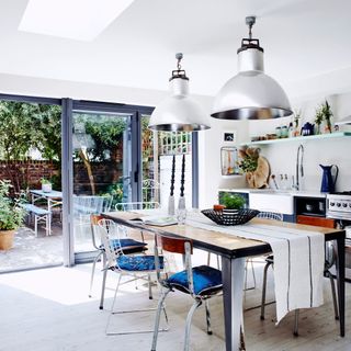 white kitchen area with dining table and hanging lghts