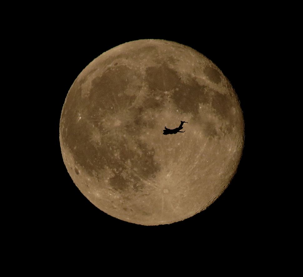 An airplane flies in front of the Blue Moon of July 31, 2015, in this photo captured by skywatcher Chris Jankowski of Erie, Pennsylvania.
