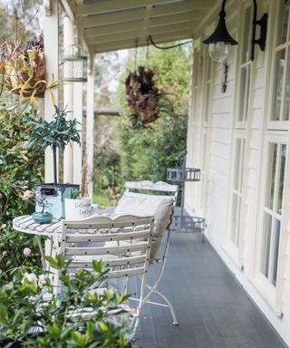 An example of how to decorate a front porch showing a porch area with a bistro table and chair set and cream wall panels