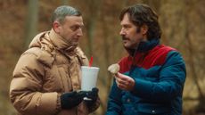 Tim Robinson (left) in brown puffa jacket, holding a fast food drink, Paul Rudd (right) in a blue and red puffa jacket holding a mushroom