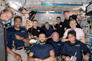 Nine astronauts pose aboard the international space station.