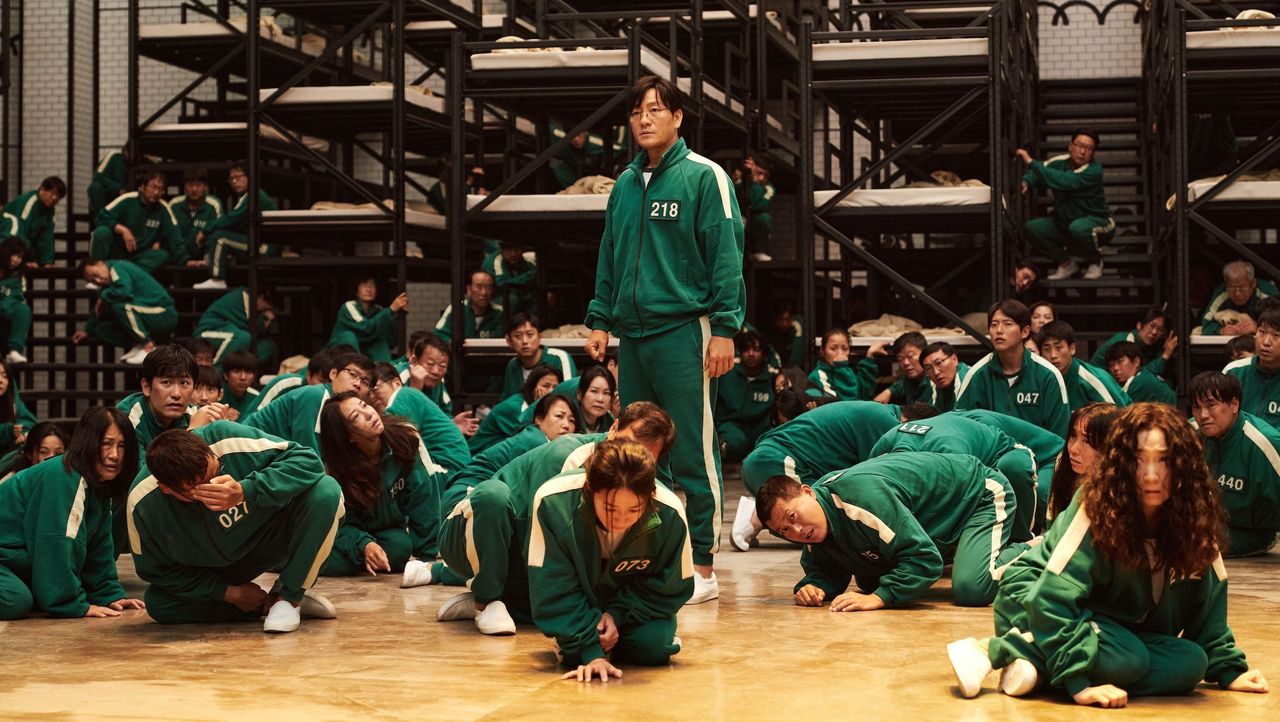 players wearing their green sweatsuits in front of bunkbeds in squid game season 1