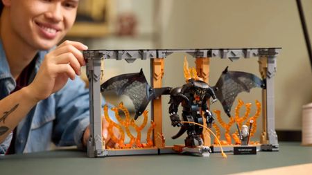 A man places a piece on the open Lego Balrog Book Nook