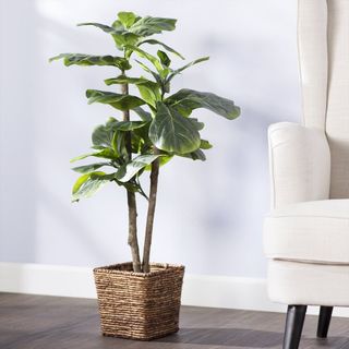 tall faux plant in a woven basket siting on the floor