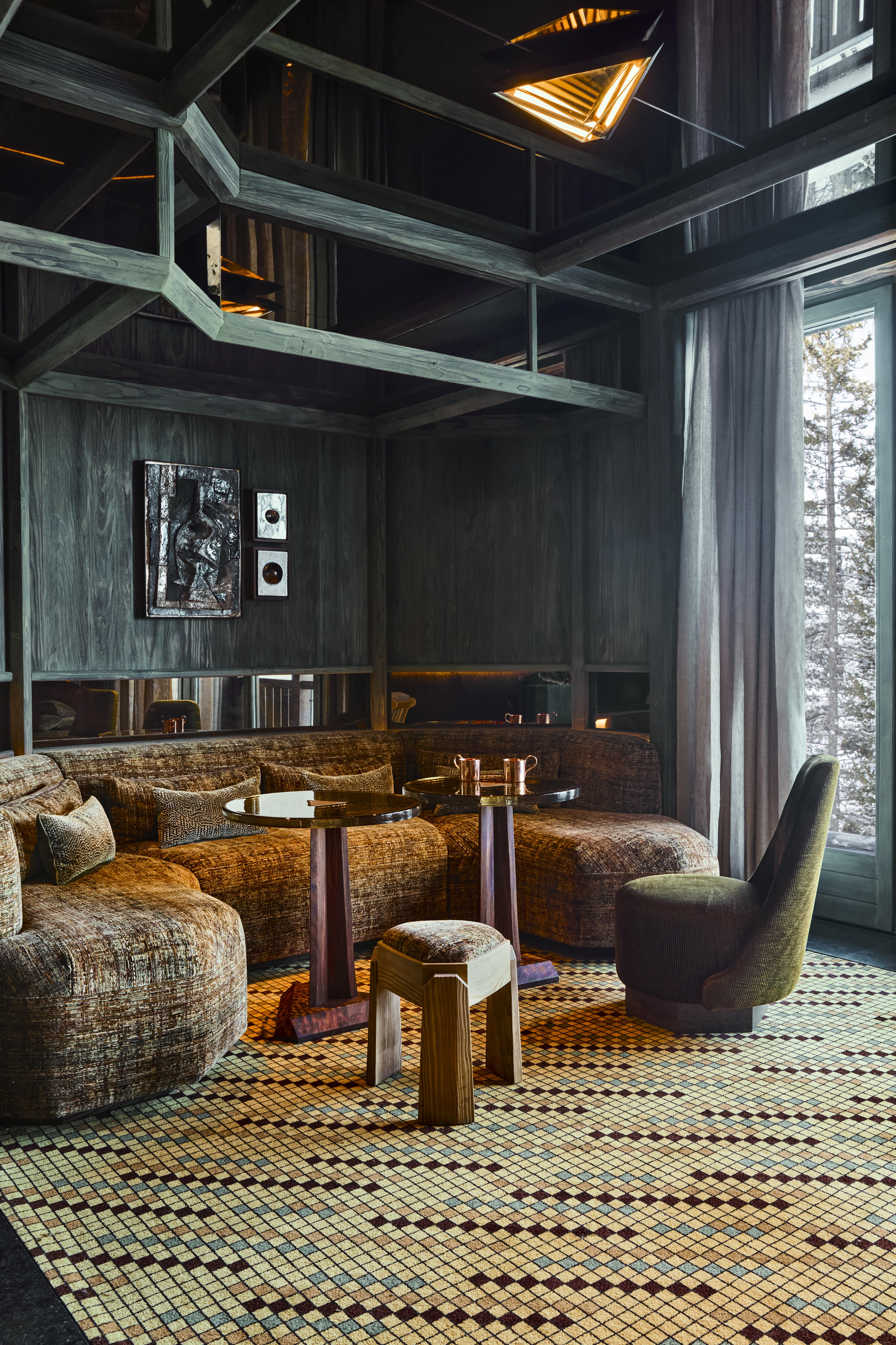 The elaborate, theatrical interiors of a ski chalet with wood wall paneling, plush textiles in different patternes, colors, and textures, plenty of paintings and sculptures adorning its halls, and a dimly lit atmosphere.