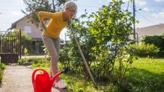 Woman gardening holds her back and looks slightly pained