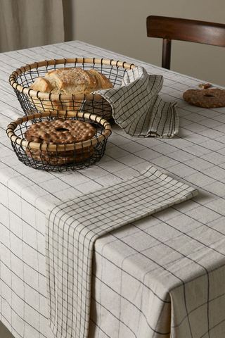table laid with a black and cream checkered tablecloth with matching napkins and bowls of food on top