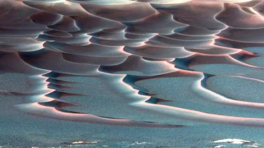 A false color image shows red sand dunes streaking across a blue surface