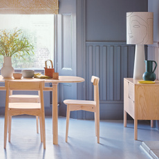 Dining room with blue flooring, blue wood panelling and shutters, wood table and chairs.