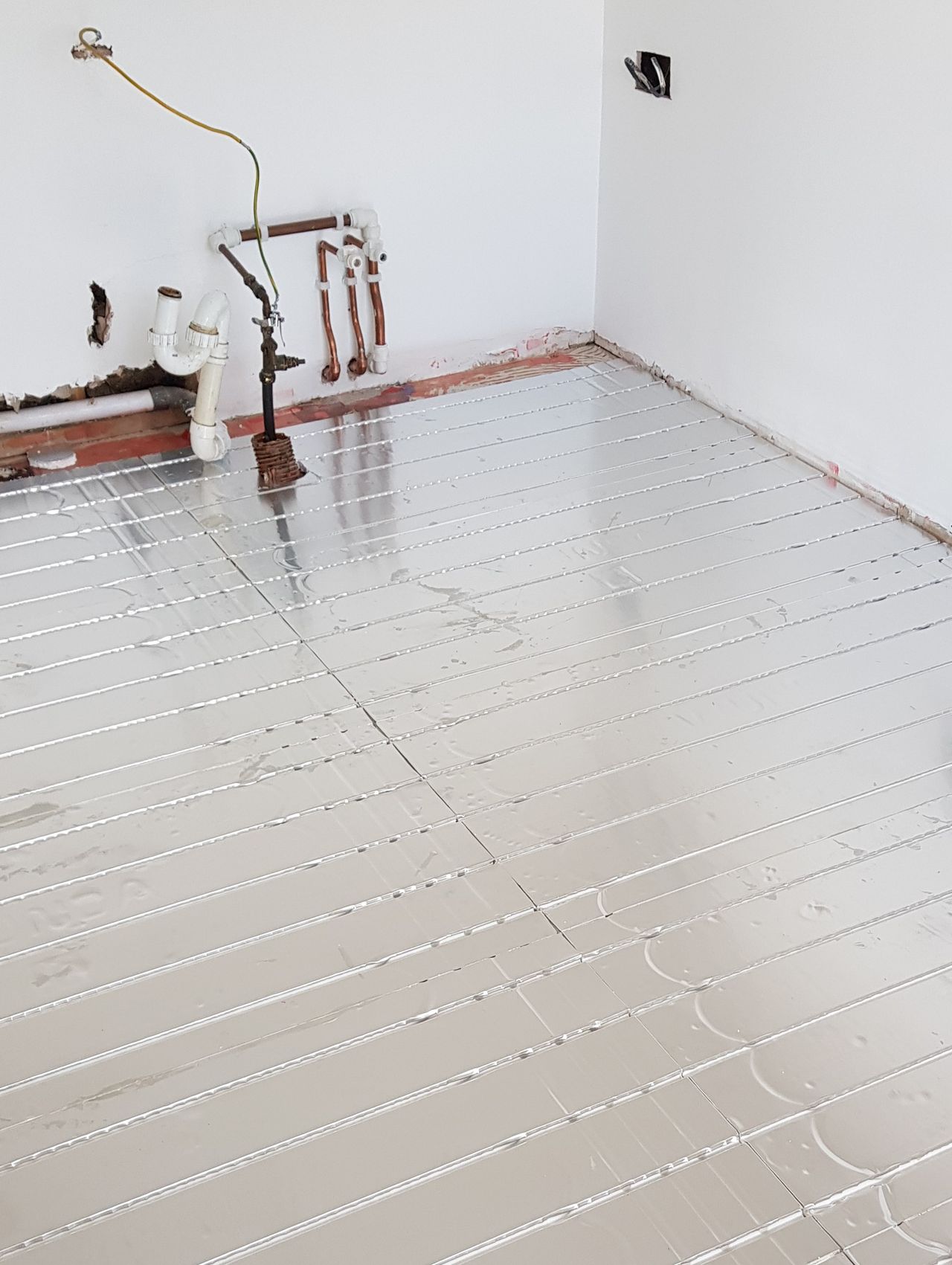 Silver underfloor heating matting with pipes embedded into it