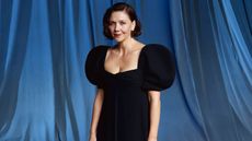 Maggie Gyllenhaal in a black velvet dress against blue curtains