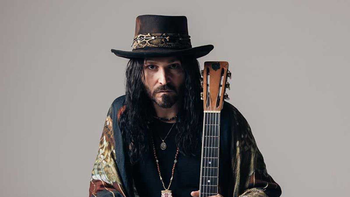 Troy Redfern in a hat holding a guitar