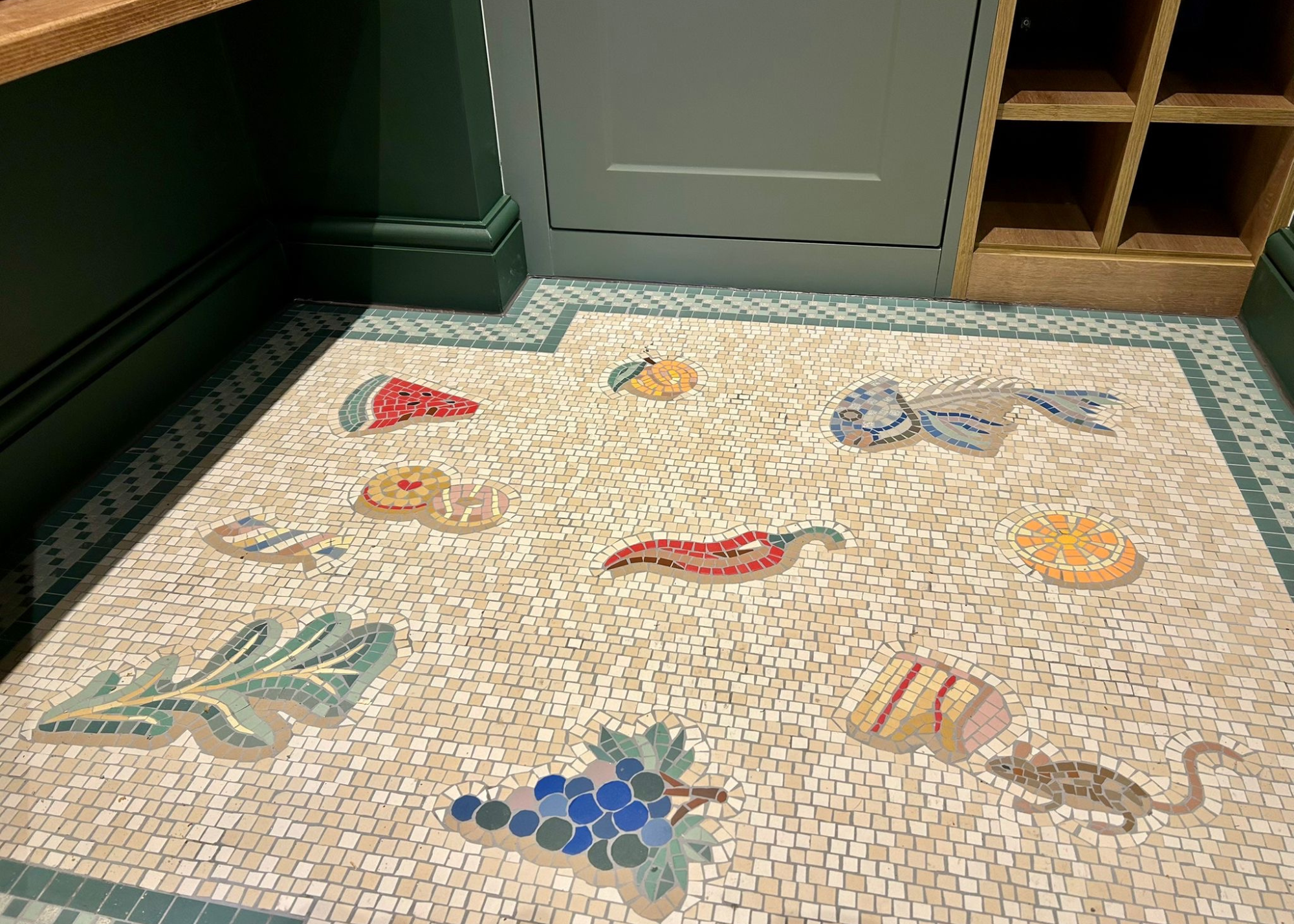 an unswept floor mosaic in a pantry room with a mouse nibbling a cake, a chilli pepper, and a watermelon