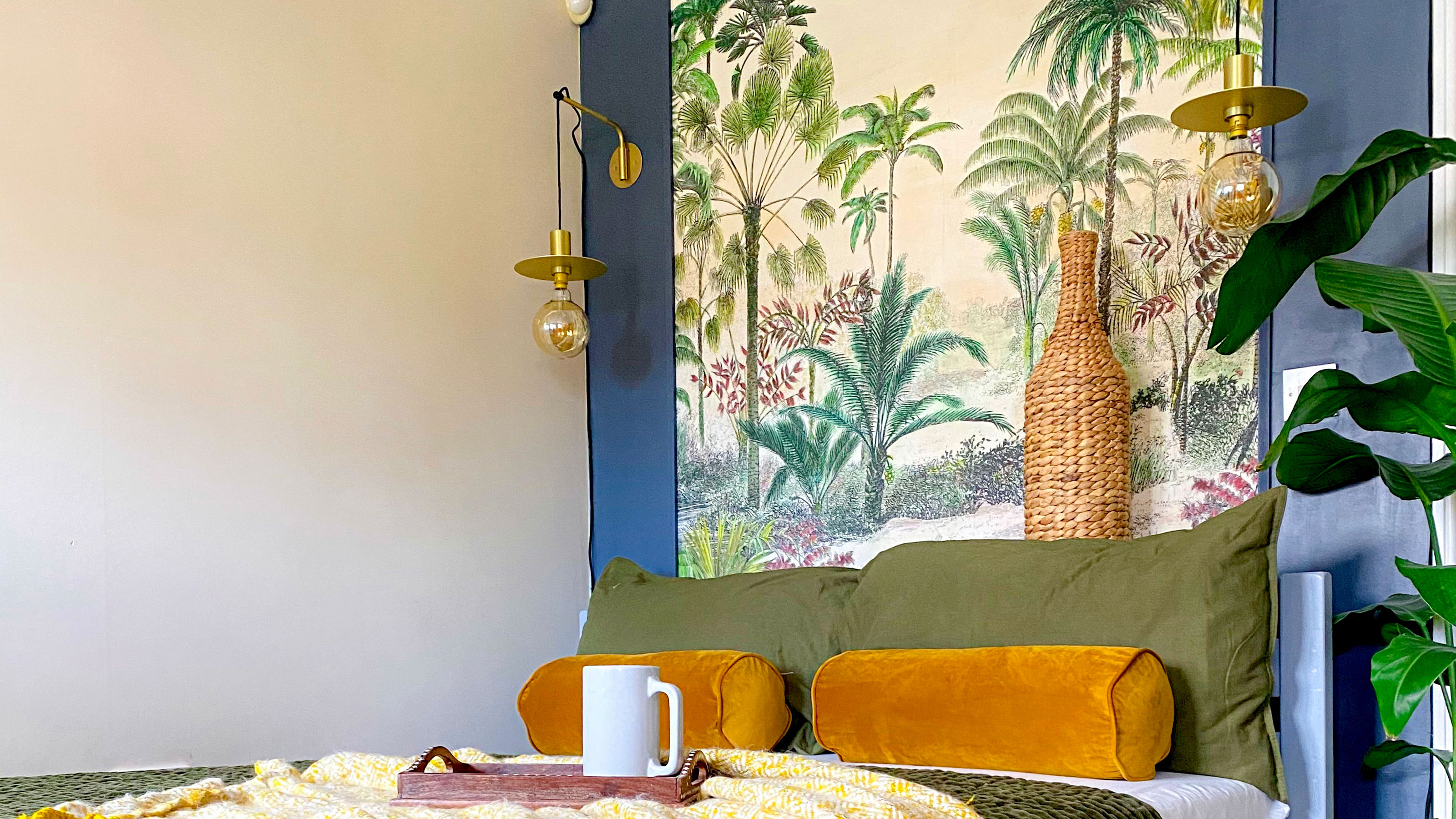 Bedroom with tropical headboard behind bed dressed in green linens