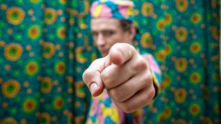 a person in colorful clothing pointing the finger at you.